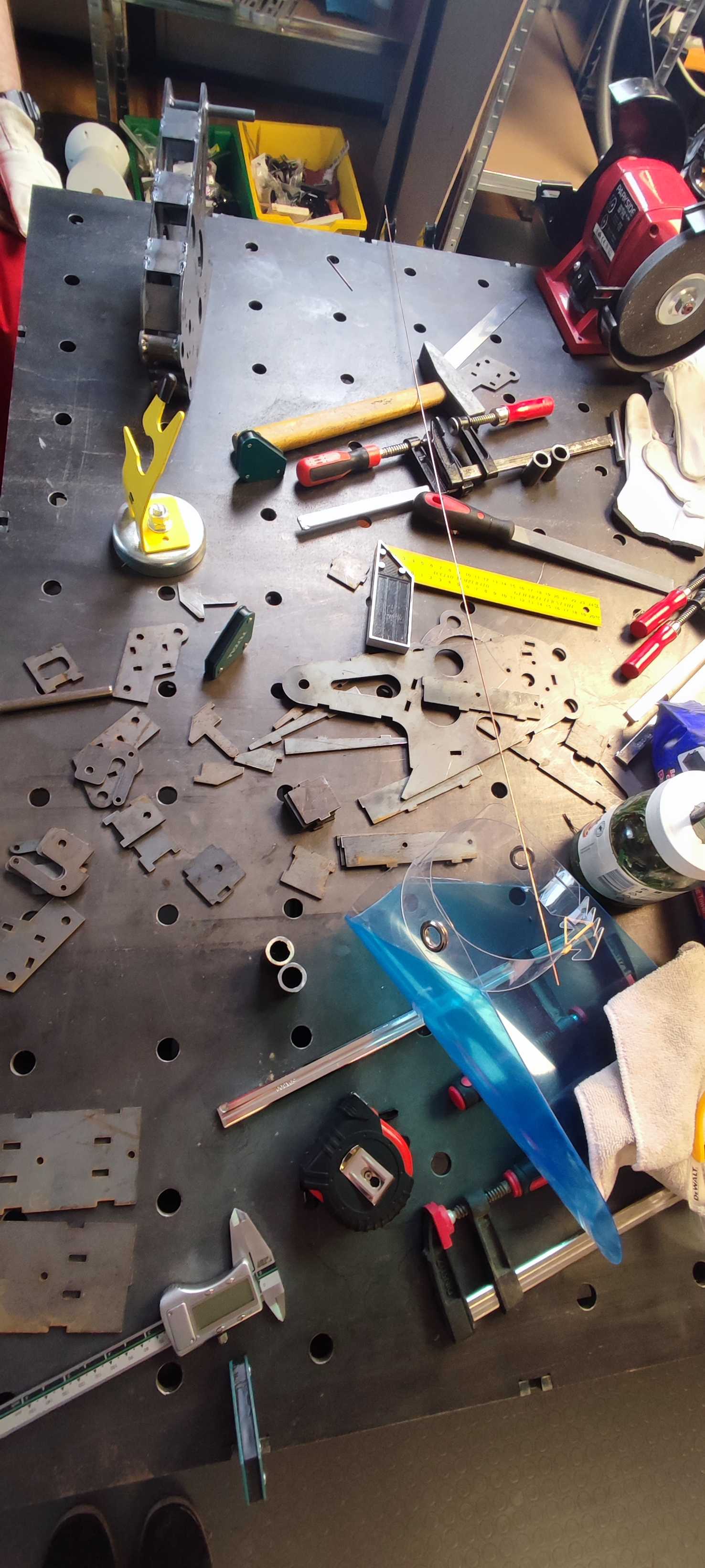 Laser-cut steel plates and brackets laid out on a welding table before assembly