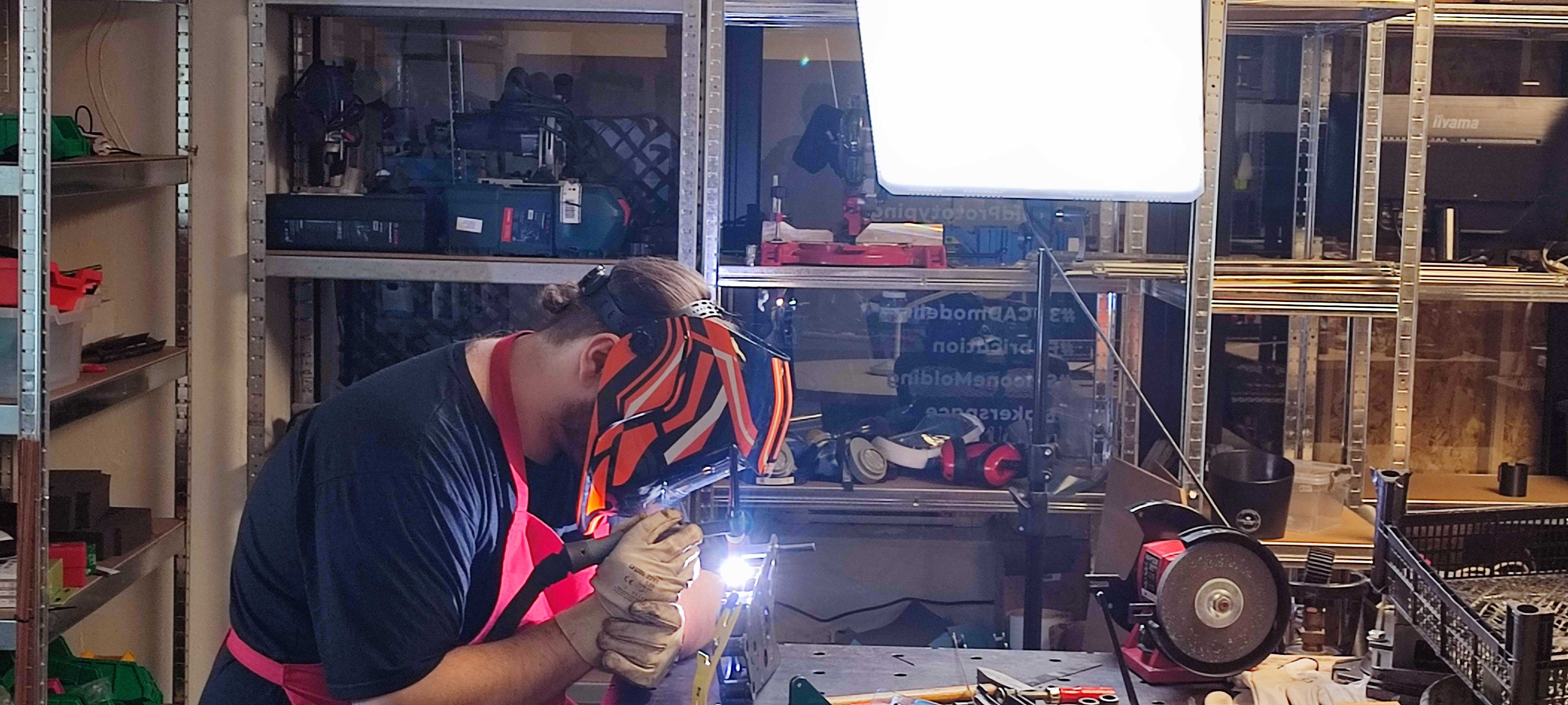 Welder in helmet and gloves striking an arc on the frame